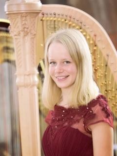 Foto von Samira Nowarra mit Harfe im Hintergrund.