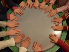 Viele Kinderhände trommeln gemeinsam auf einer großen Trommel.