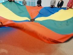 Kinder halten zusammen ein großes Tuch in die Luft.