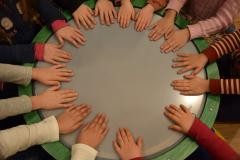 Kinderhände im Kreis auf einer großen Trommel.