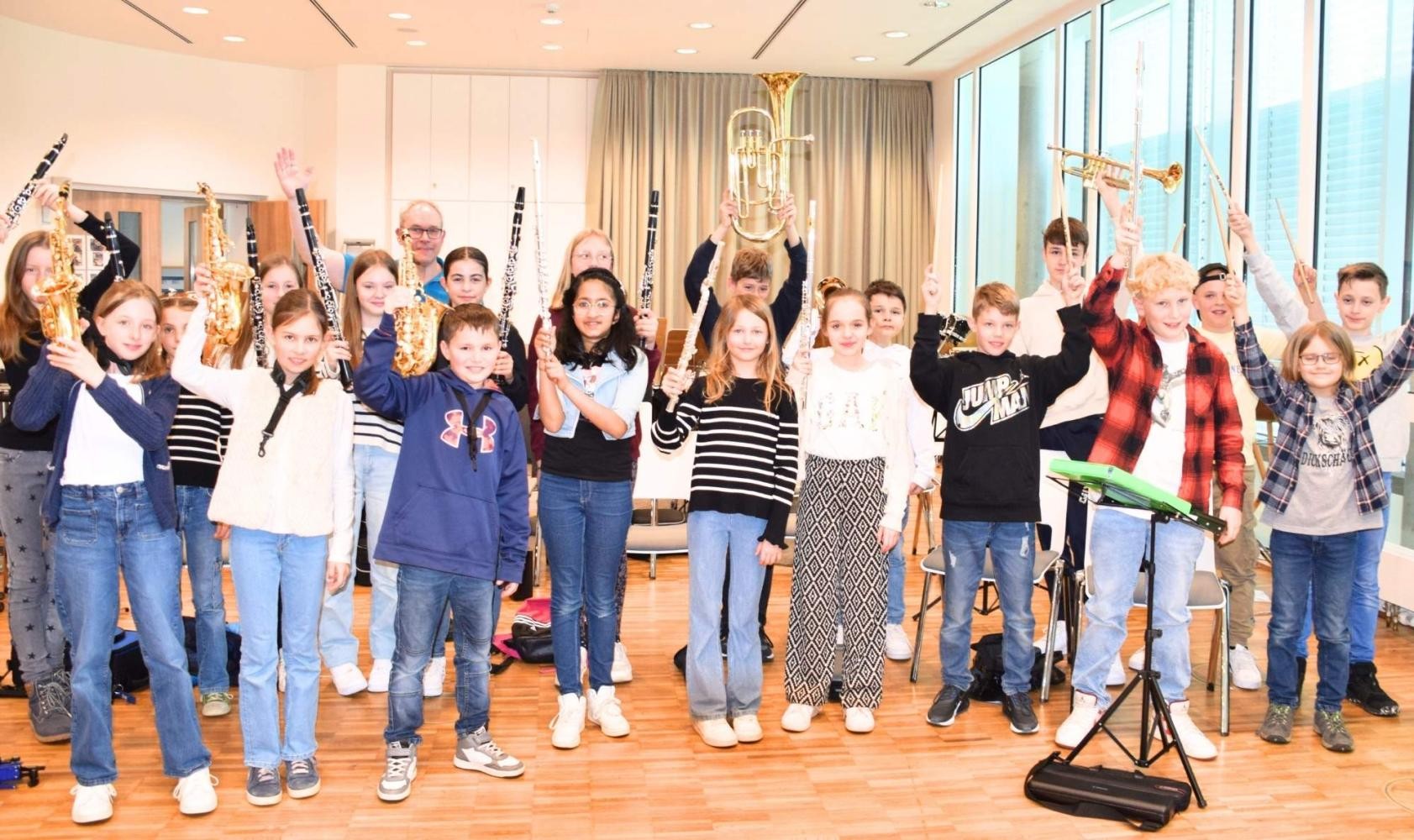 Kinder des Vorstufenorchesters heben alle ihre verschiedenen Instrumente in die Luft.