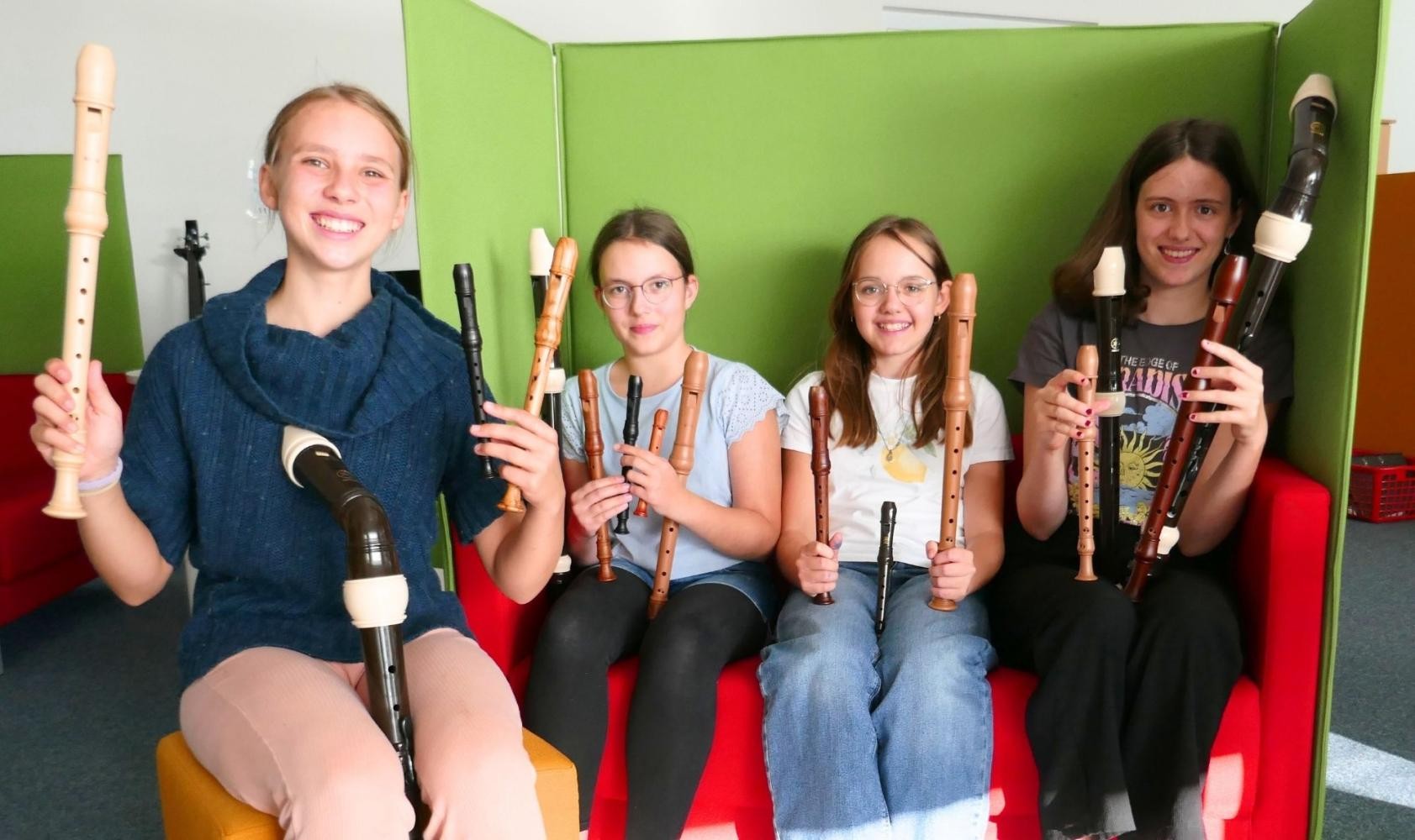 Auf dem Boden liegen sternförmig viele verschiedene Blockflöten auf kunterbunten Teppichfliesen.