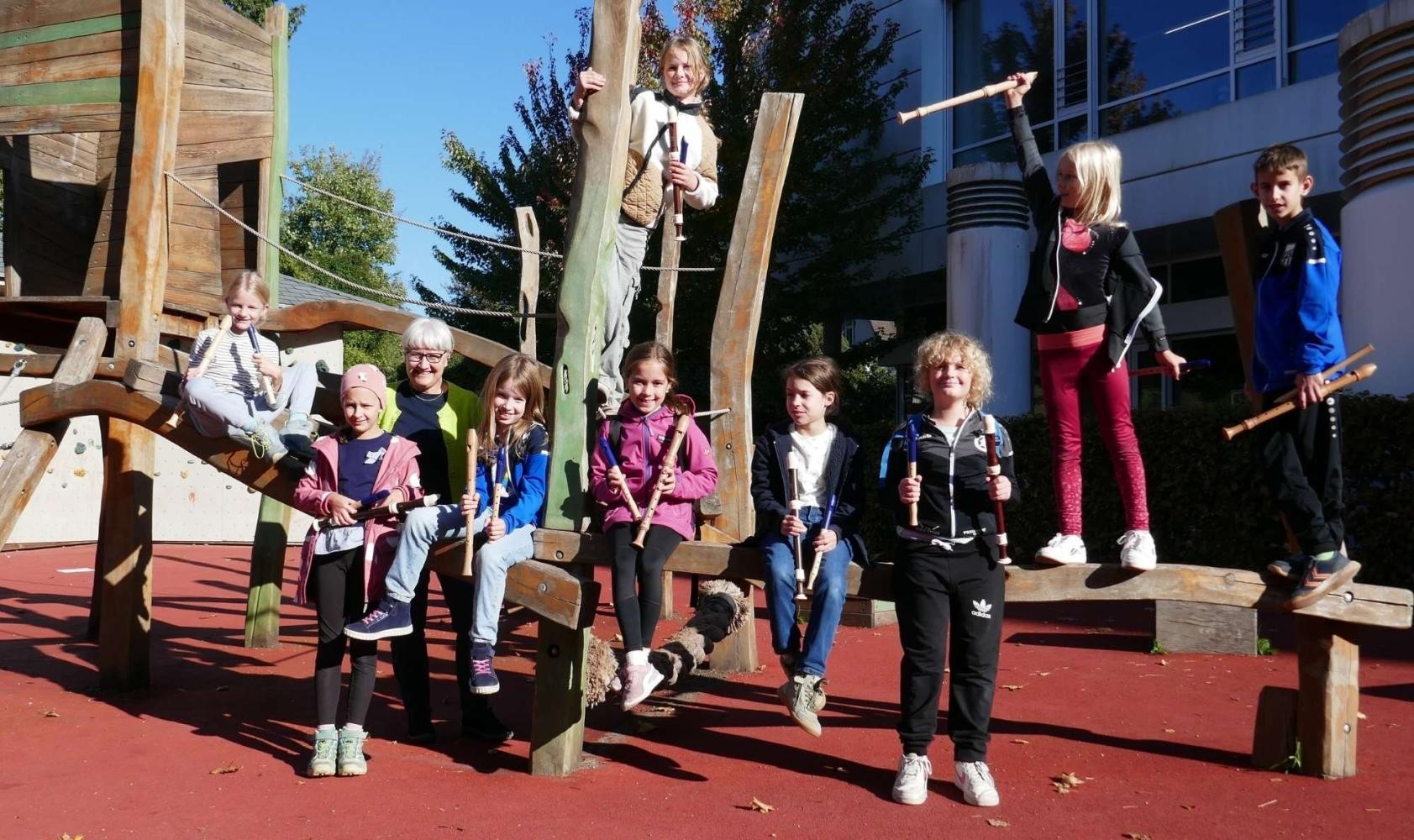 Die Kinder des Ensembles Flautino sitzen mit ihren Flöten auf einem Klettergerüst.