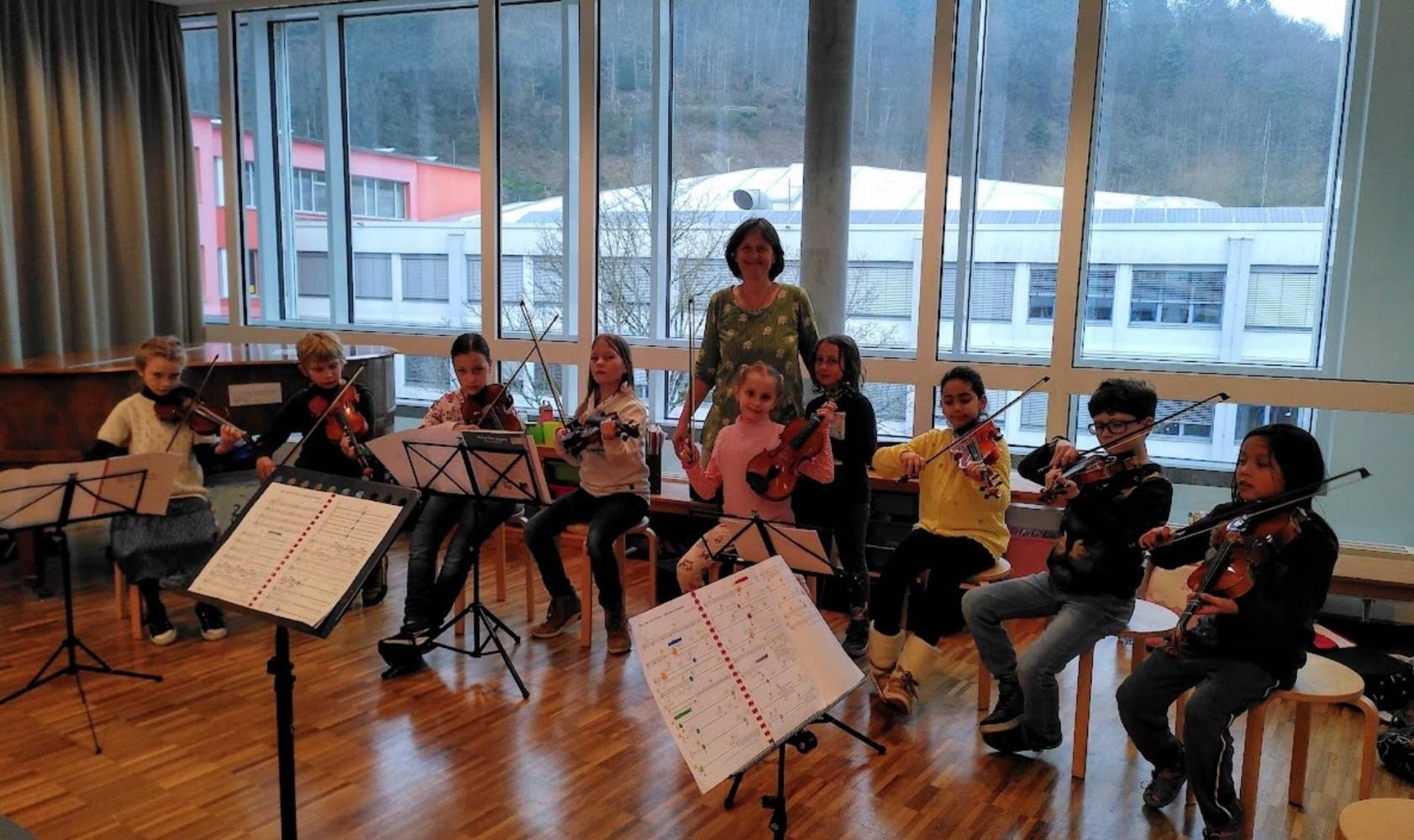 Auf der Bühne sind Musikschüler und die Leiterin des Kinderkammerorchesters.