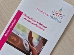 Der Flyer "Musikschule" liegt auf dem Tisch.