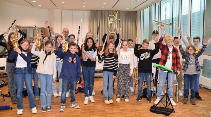 Kinder des Vorstufenorchesters heben alle ihre verschiedenen Instrumente in die Luft.