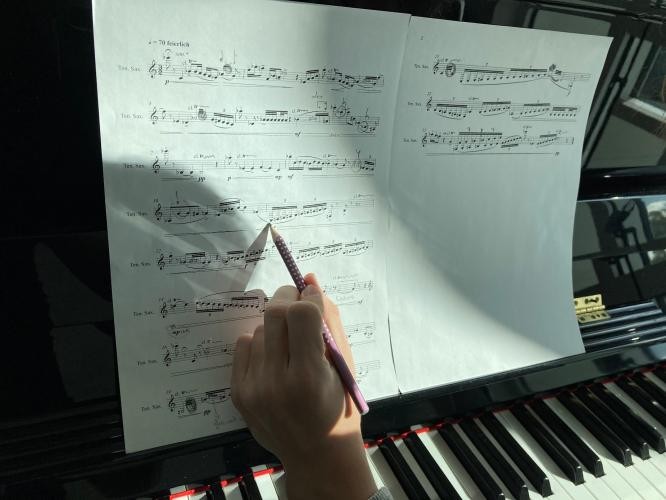 Eine Person fährt Noten an einem Klavier ab.