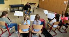 Kinder siten in einem Klassenzimmer und üben Klarinette.