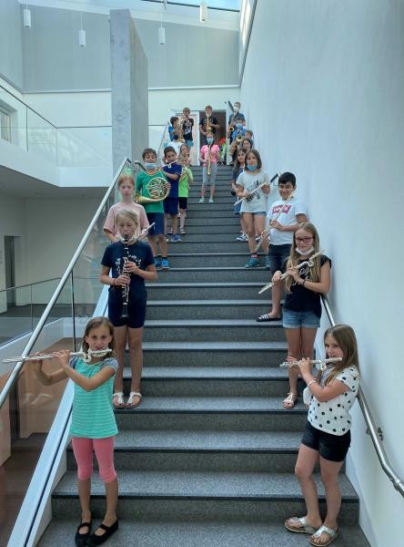 Mehrere Kinder mit Musikinstrumenten stehen auf den Treppen der Musikschule.