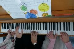 Mehrere Kinder sitzen an einem Klavier und spielen.