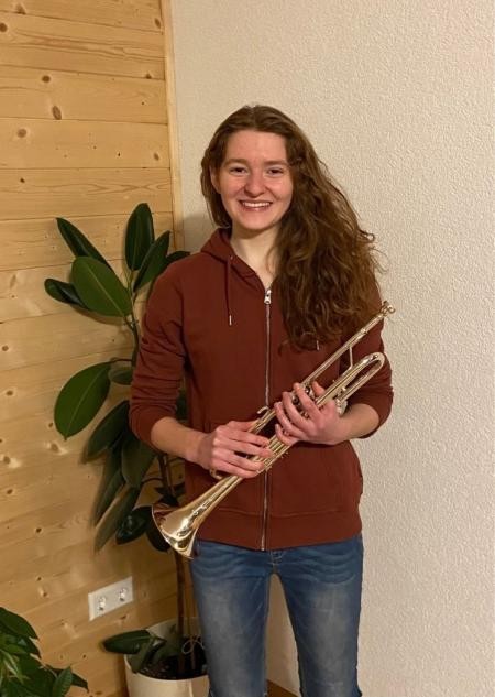 Lotte Saier hält eine Trompete in der Hand.