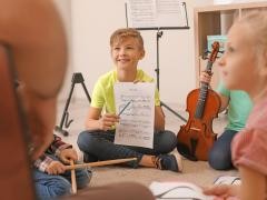 Mehrere Kinder mit Instrumenten sitzen in einem Kreis.