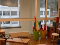 In einem Raum der Musikschule sieht man Rhythmusinstrumente, Hocker, Bänke und Notenständer.