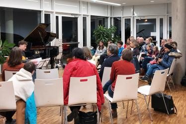 Gäste sitzen gemeinsam und hören einander Musik spielen.