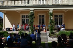 Kinder spielen auf ihren Flöten, tanzen und singen Kinderlieder unter der Leitung ihrer Lehrerin.