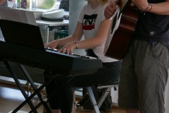 Ein Mädchen spielt auf dem Piano und ein Lehrer auf seiner Gitarre.