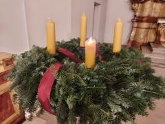 Ein Adventskranz mit 4 gelben Kerzen und roter Schleife.