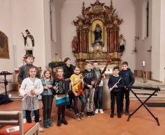 Zehn junge Schüler*innen mit ihren Instrumenten, darunter Fagott, Oboe, Flöten und Violinen.