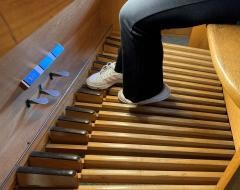 Die Füße benutzen die Pedale unter der Orgel.
