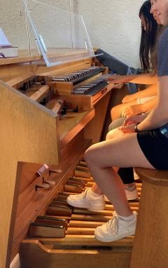Zwei Schülerinnen spielen gemeinsam an der Orgel. Eine betätigt das Pedal, die andere spielt auf den Tasten.