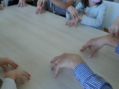 Man sieht viele Hände auf einem Tisch - Herr Goeritz spielt mit den Kindern Kommando Bimberle.