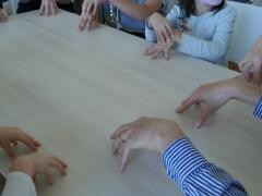 Man sieht viele Hände auf einem Tisch - Herr Goeritz spielt mit den Kindern Kommando Bimberle.