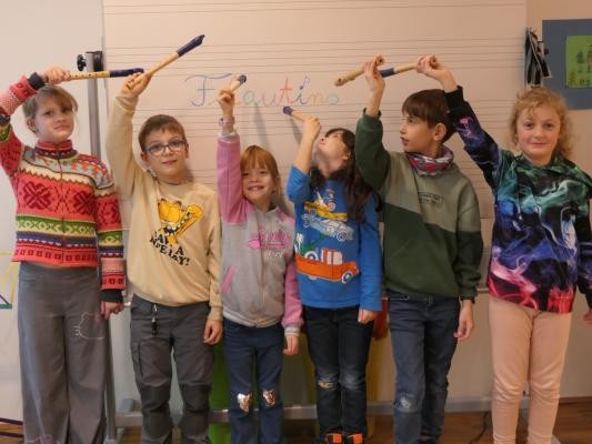 Eine Gruppe Kinder halten ihre Blockflöten in der Luft nach Oben.