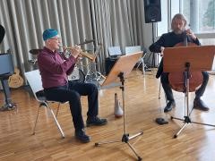 Ein Musiklehrer-Duo bestehend aus einem Cello und Trompetenspieler.