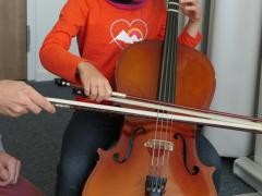 Cellolehrer und Schülerin spielen gemeinsam auf einem Cello.