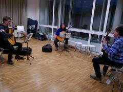 Zwei jugendliche Schüler*innen haben gemeinsam Gitarrenunterricht.