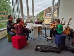 5 junge Gitarrenschüler haben gemiensam Unterricht.