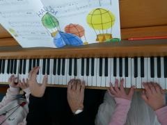 Eine Lehrerin und 2 kleine Kinder spielen 6 händig Klavier.