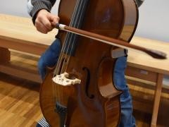 Ein kleines Kind probiert ein Cello aus.
