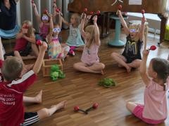 Kinder halten Rasseln hoch in die Luft.