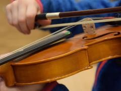 Ein Kind versucht auf einer Geige zu spielen.