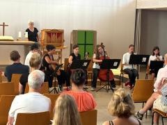 Ein Ensemble mit verschiedenen Instrumenten spielt vor vielen Zuhörern.