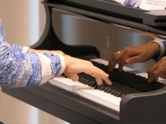 Die Hände einer Klavierspielerin sind auf der Tastatur zu sehen.